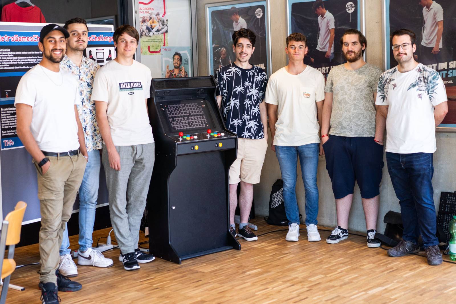 Das Team hinter der Retro Game Challenge vor seiner Retro-Arcade-Maschine.